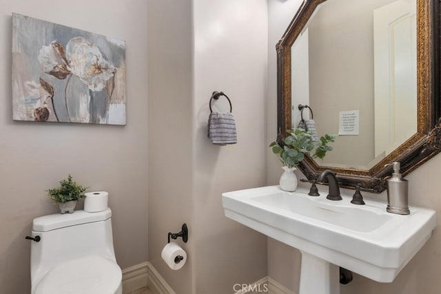 bathroom with baseboards, a sink, and toilet