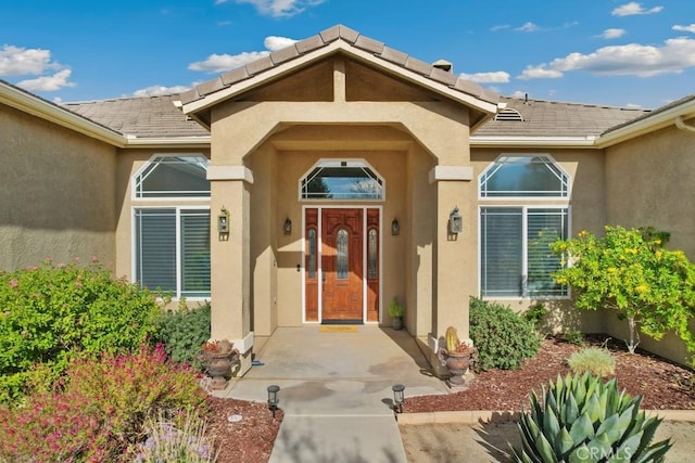 doorway to property with a tile roof and stucco siding