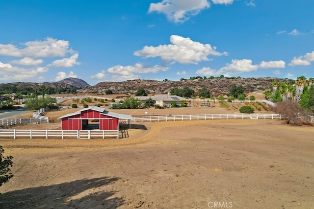 view of yard with an enclosed area, a rural view, an outdoor structure, and a mountain view