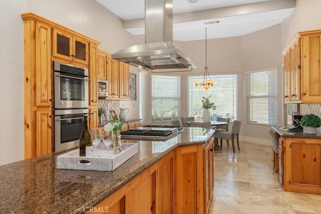 kitchen with dark stone countertops, island exhaust hood, appliances with stainless steel finishes, and backsplash