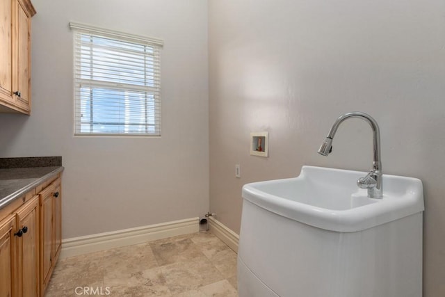 laundry area featuring washer hookup, a sink, cabinet space, and baseboards