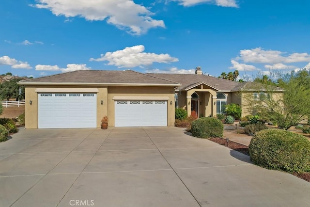 ranch-style house with concrete driveway, an attached garage, and stucco siding