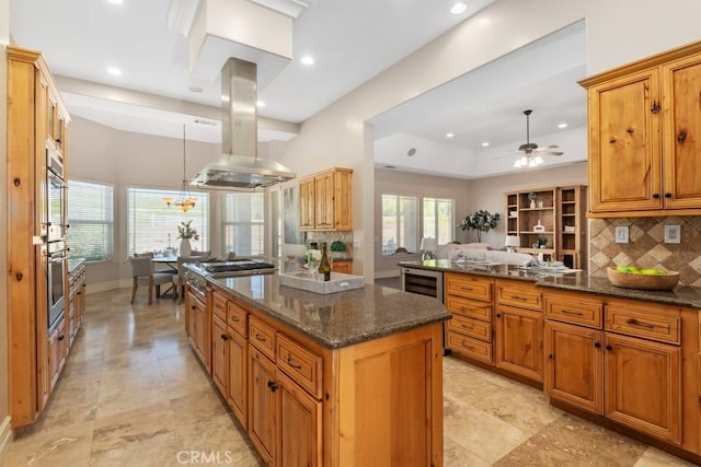 kitchen featuring tasteful backsplash, brown cabinetry, a center island, island exhaust hood, and stainless steel gas cooktop