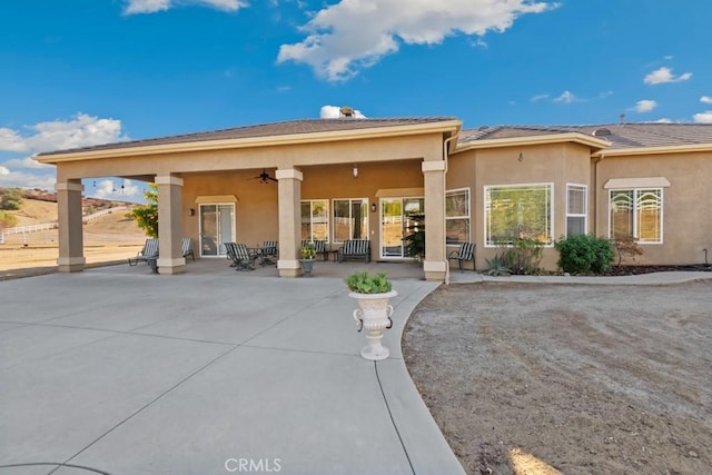 rear view of house with a patio area, ceiling fan, and stucco siding