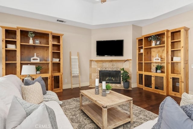 living area with visible vents, a fireplace, baseboards, and wood finished floors