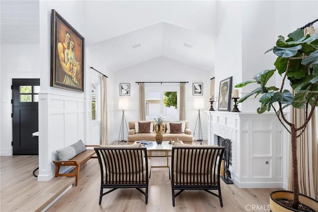 sitting room with a healthy amount of sunlight, wainscoting, light wood-style flooring, and a brick fireplace