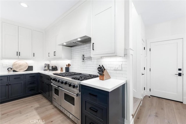 kitchen featuring range with two ovens, light wood finished floors, light countertops, decorative backsplash, and white cabinets