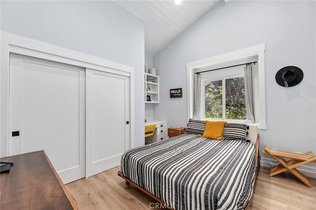 bedroom with light wood-style floors, lofted ceiling, and a closet