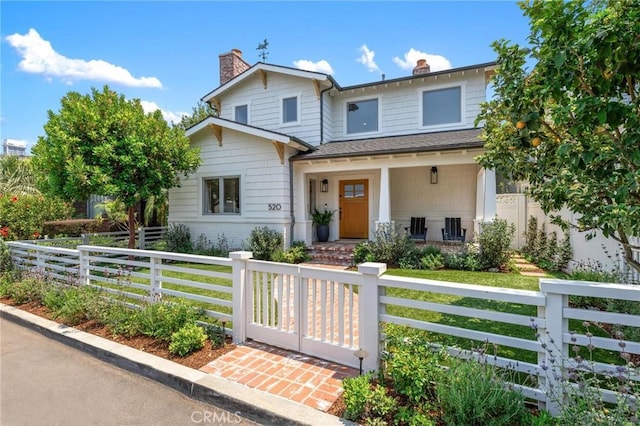 view of front of house featuring covered porch, a chimney, and a fenced front yard