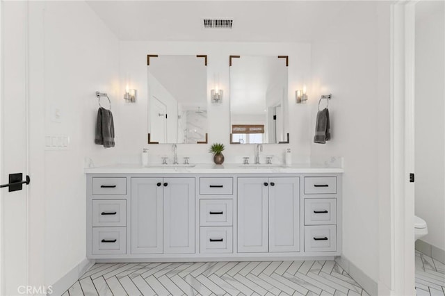 full bathroom featuring double vanity, visible vents, toilet, and a sink