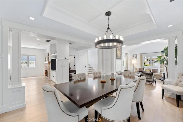 dining space with a wealth of natural light, coffered ceiling, and light wood-style flooring