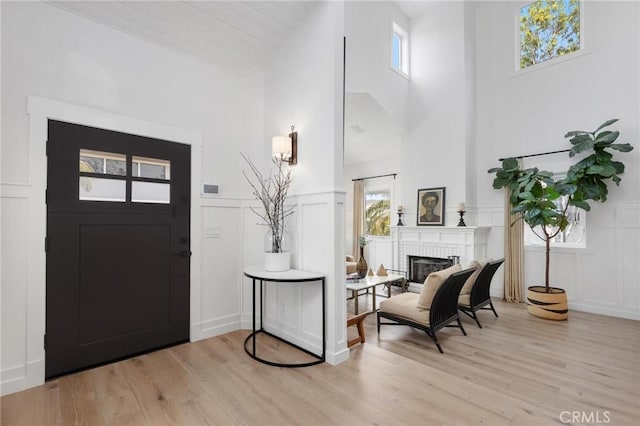 foyer with a brick fireplace, a healthy amount of sunlight, and light wood-style flooring