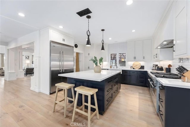 kitchen featuring light countertops, premium appliances, decorative backsplash, and a center island