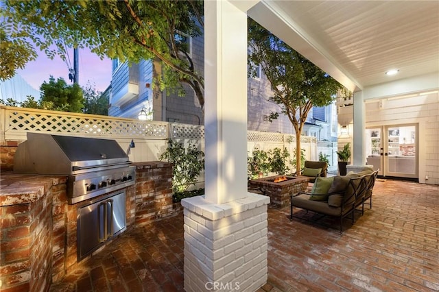 view of patio with an outdoor fire pit, area for grilling, fence, exterior kitchen, and french doors