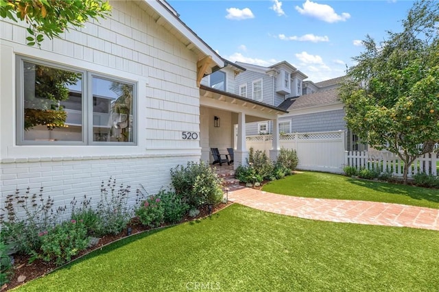 view of front facade with a front yard, brick siding, and fence