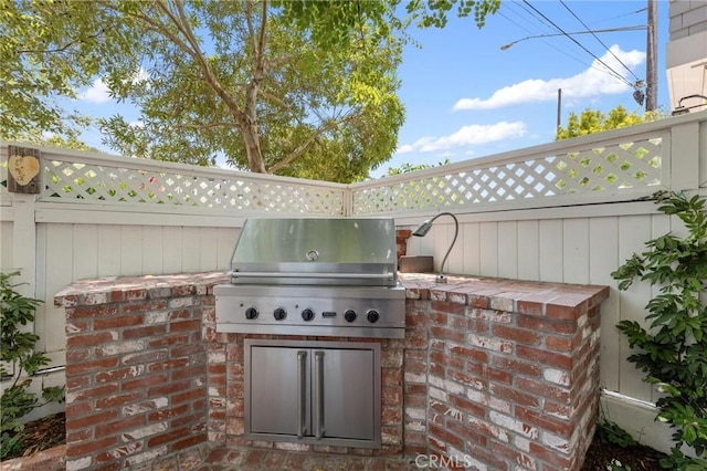 view of patio / terrace with exterior kitchen, grilling area, and fence