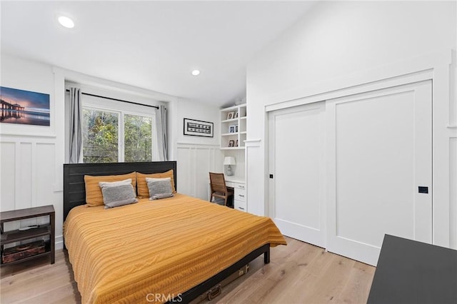 bedroom featuring a closet, recessed lighting, light wood-style flooring, and a decorative wall