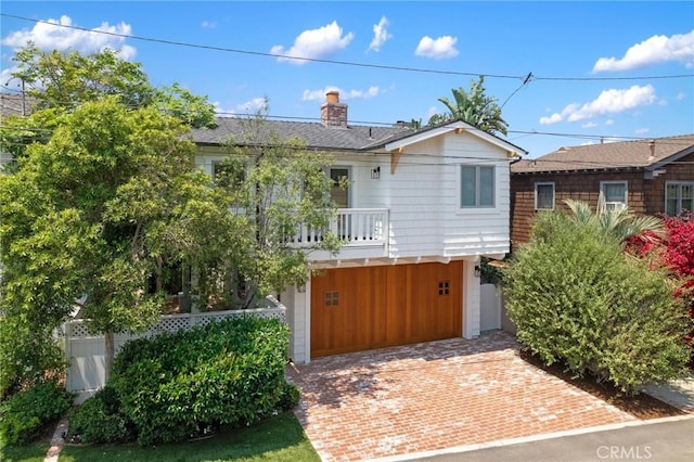 single story home with decorative driveway, a chimney, and a balcony