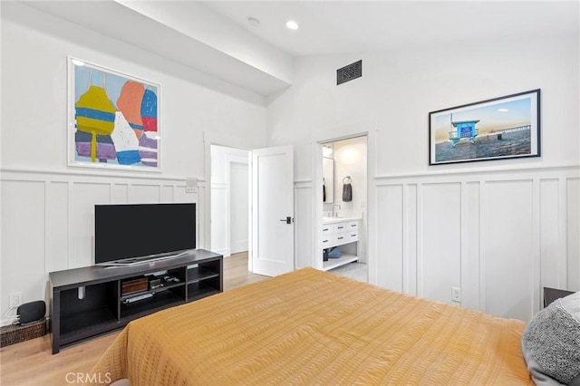 bedroom with vaulted ceiling, a decorative wall, and wood finished floors