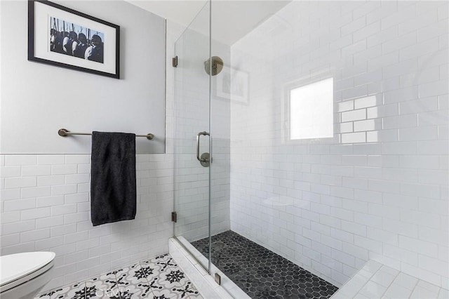 full bathroom featuring a stall shower, tile walls, toilet, and tile patterned floors