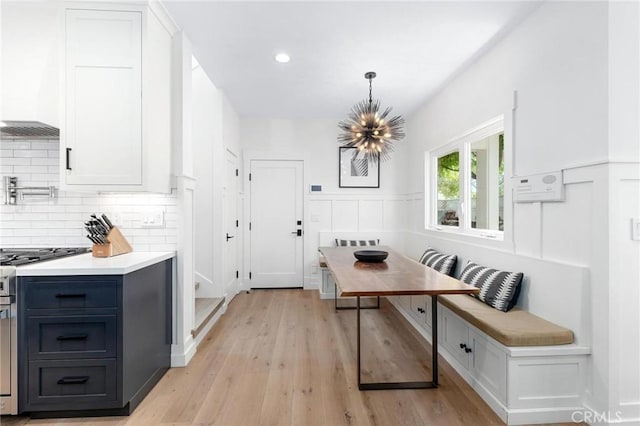 dining room with light wood-style flooring, breakfast area, a chandelier, and wainscoting