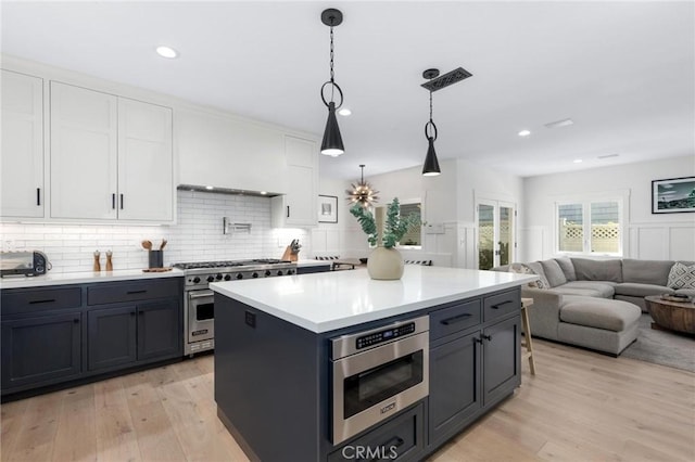 kitchen with light wood-style floors, appliances with stainless steel finishes, white cabinets, and light countertops