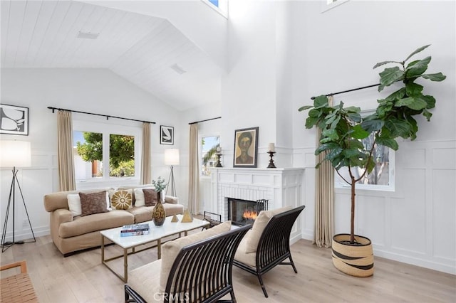 living room featuring lofted ceiling, light wood finished floors, a fireplace, and a decorative wall