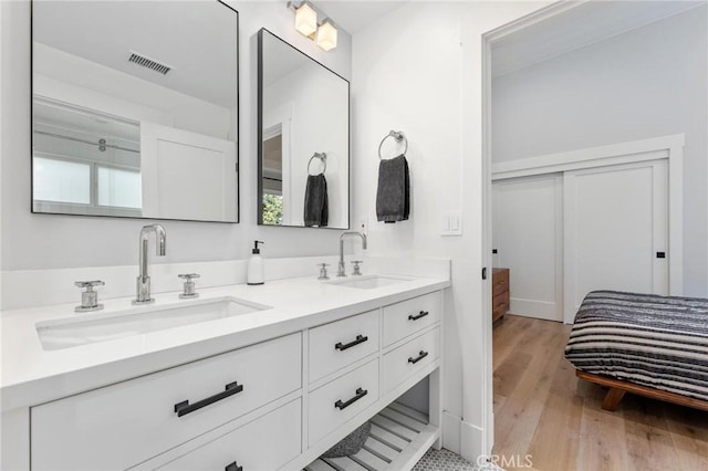 full bathroom featuring double vanity, visible vents, a sink, and wood finished floors