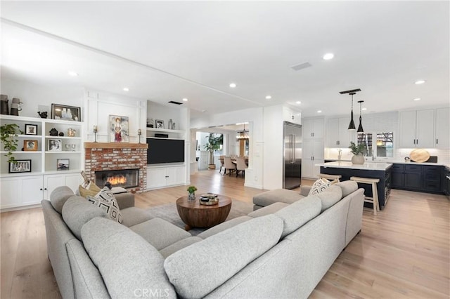 living area with light wood-type flooring, a fireplace, visible vents, and recessed lighting