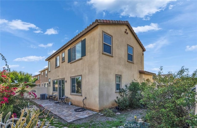 rear view of house with cooling unit, a tile roof, a patio area, and stucco siding