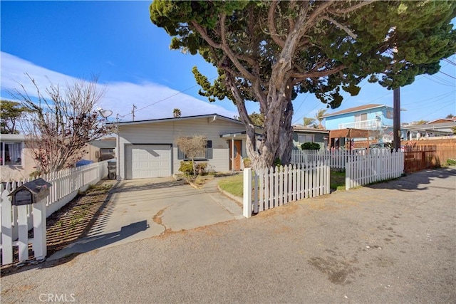 single story home with a garage, a fenced front yard, and concrete driveway