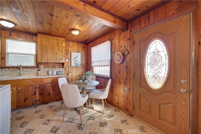 dining area featuring beamed ceiling, wood walls, and wooden ceiling