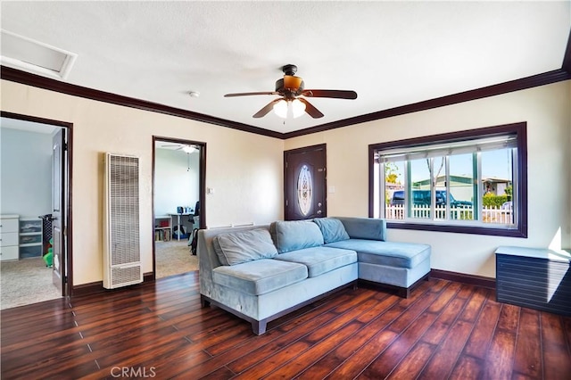 living room with crown molding, a heating unit, wood finished floors, and baseboards