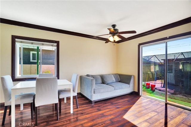 living area featuring a ceiling fan, baseboards, ornamental molding, and wood finished floors