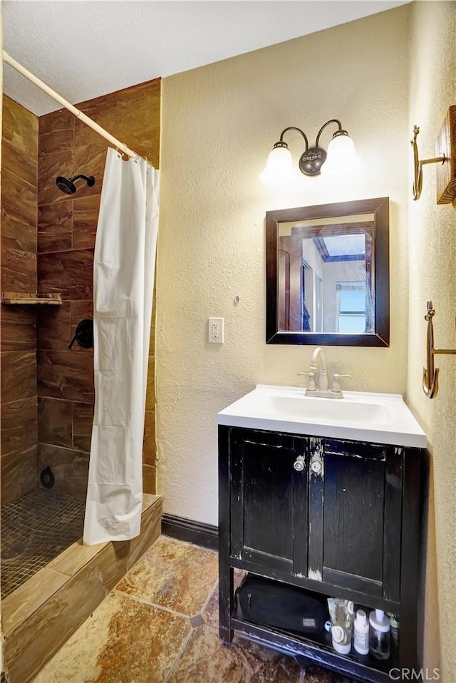 bathroom featuring a textured wall, tile patterned floors, tiled shower, and vanity