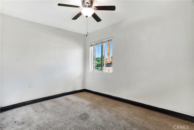 carpeted spare room with baseboards and a ceiling fan