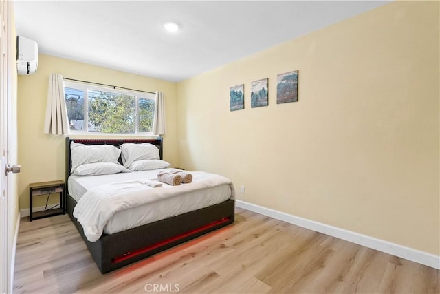 bedroom featuring baseboards, wood finished floors, and a wall mounted AC