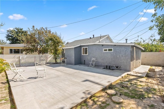 back of house featuring a fenced backyard, a patio, and stucco siding