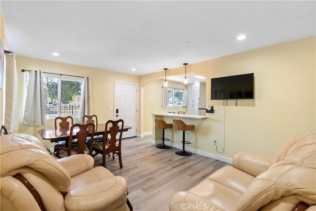 living room with arched walkways, recessed lighting, light wood-style flooring, and baseboards