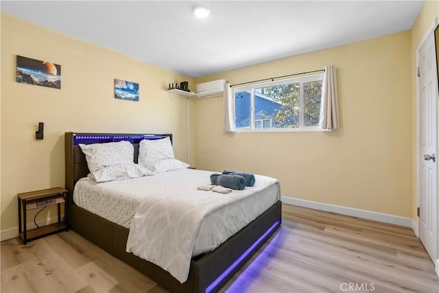 bedroom featuring an AC wall unit, wood finished floors, and baseboards