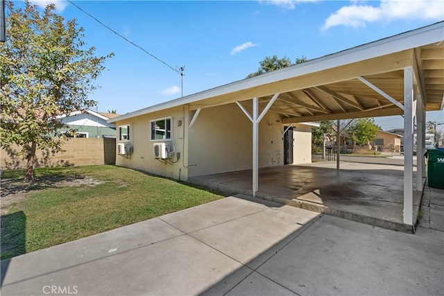 exterior space featuring an attached carport, concrete driveway, and fence