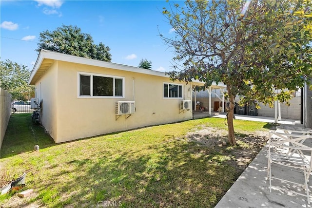 view of front of house featuring a wall unit AC, stucco siding, fence, a patio area, and a front yard