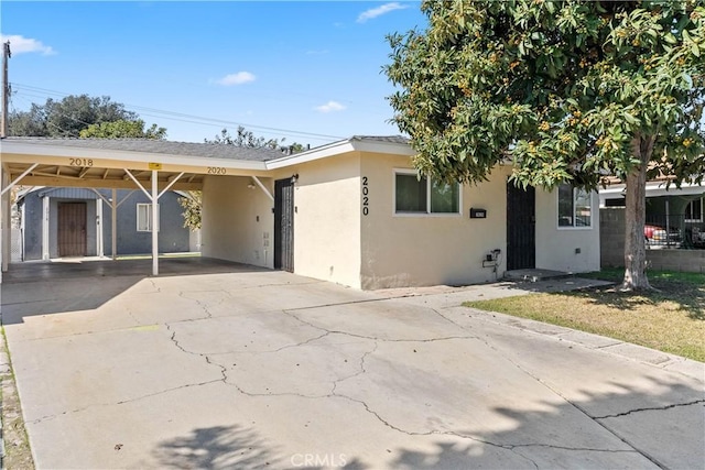 ranch-style house featuring a carport, driveway, and stucco siding