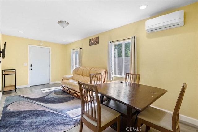 dining area with light wood-type flooring, baseboards, and a wall mounted AC