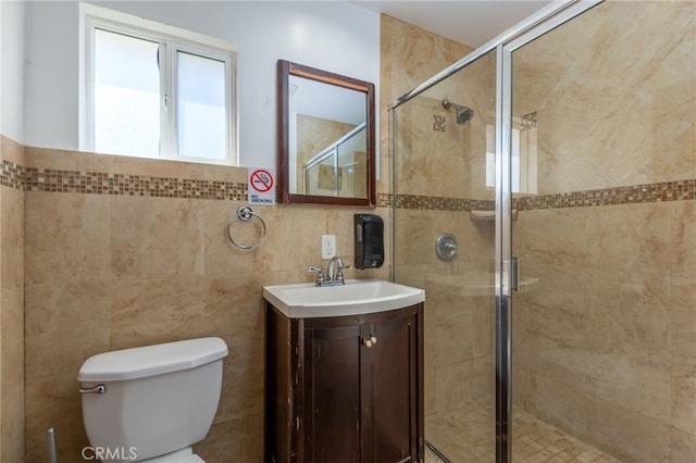 bathroom featuring a stall shower, vanity, toilet, and tile walls