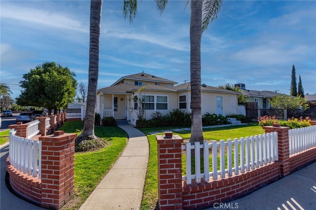 view of front of home with a fenced front yard, a front lawn, and stucco siding