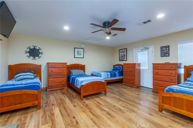 bedroom with light wood finished floors, attic access, and visible vents