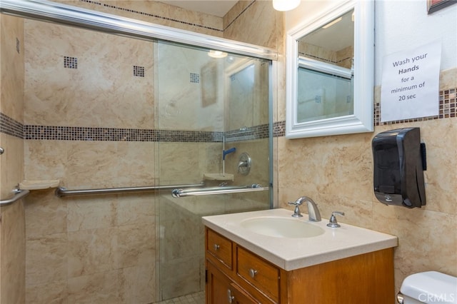 bathroom featuring toilet, a shower stall, tile walls, and vanity