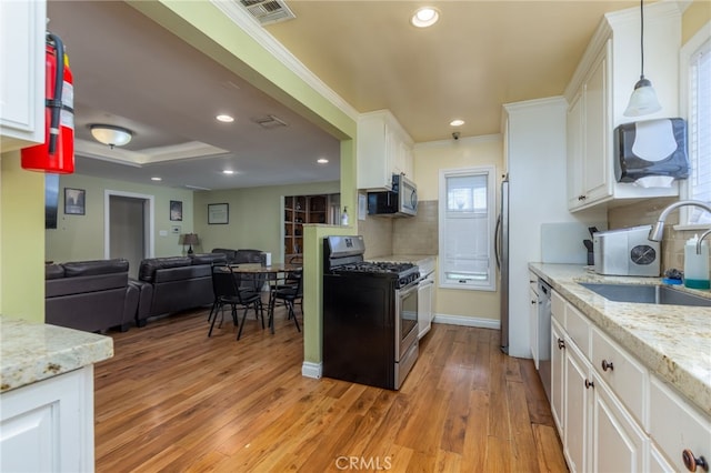 kitchen with visible vents, white cabinets, appliances with stainless steel finishes, open floor plan, and a sink