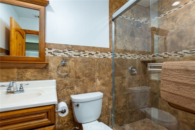 bathroom with vanity, a shower stall, toilet, and tile walls